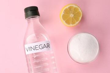 Eco friendly natural cleaners. Vinegar in bottle, cut lemon and bowl of soda on pink background,...