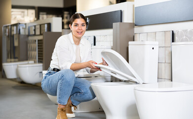 Woman in store chooses white toilet for new home. repair, arrangement of apartment and purchase of...