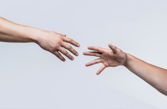 Two male hands reaching towards each other on isolated gray background. Helping hand outstretched, isolated arm, salvation. Close up help hand. Two hands, helping arm friend, teamwork. Helping hand