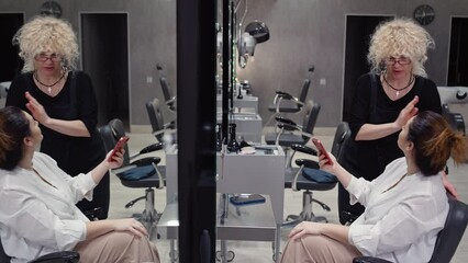 The hairdresser communicates with the client about hairstyles and haircuts. A professional works with people in a hair salon. High quality 4k footage