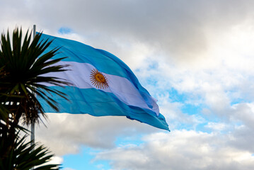 Light blue and white Argentinian flag waving with blue sky and white clouds as background
