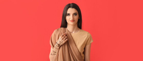 Beautiful Indian woman with henna tattoo on color background