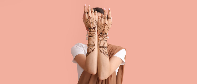 Beautiful Indian woman with henna tattoo on color background