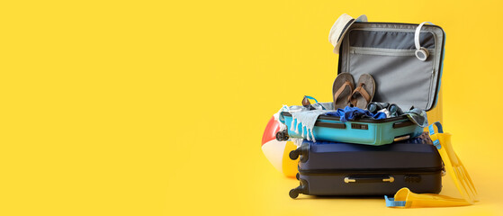 Suitcases with inflatable ball, beach accessories and headphones on yellow background. Summer...