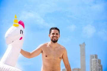 Young adult man playing with float on beach