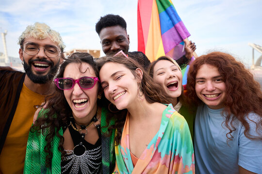 Diverse group of happy young people taking funny selfie for social media celebrating gay pride festival day. Lgbt community concept cheerful friends outdoors. Generation z enjoy party.