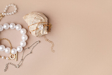 Different beautiful bracelets with seashell on pink background