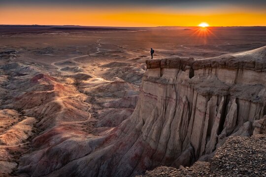 Tourist standing on rock formation Tsagaan Suvarga, White Stupa, View at sunrise, Dornogovi Aimag,, Mongolia, Asia