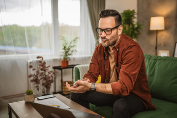 Adult caucasian man work from home on laptop and hold documents