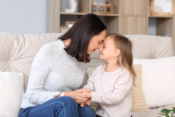 Obraz premium Beautiful mother with her cute little daughter sitting on sofa at home