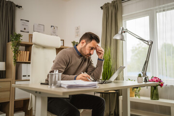 Exhausted adult man have headache or migraine while work at office