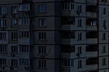 View on a panel residential building during blackout of electricity at night. Apartment multistorey, close up view of windows without light. Kyiv, Ukraine. Consequences after russian missile attacks. 