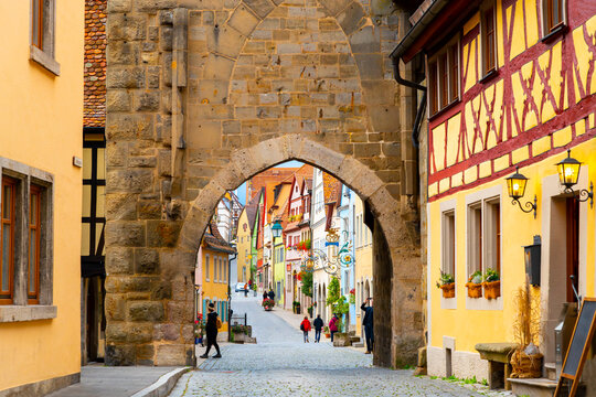 The picturesque medieval old town of Rothenburg ob der Tauber with shops and tourists seen through the Markus Tower Gate.