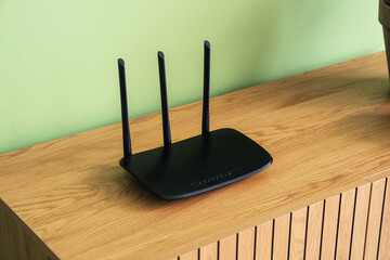 Modern wi-fi router on commode near green wall, closeup
