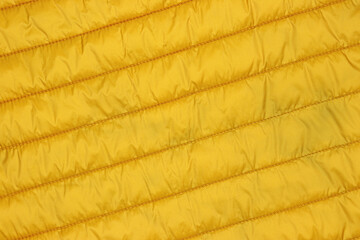 Yellow waterproof winter puffer jacket close up. Polyester fabric textile