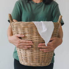 A woman holding a laundry basket of clothes. A cropped image of a beautiful young woman smiling while doing laundry at home.