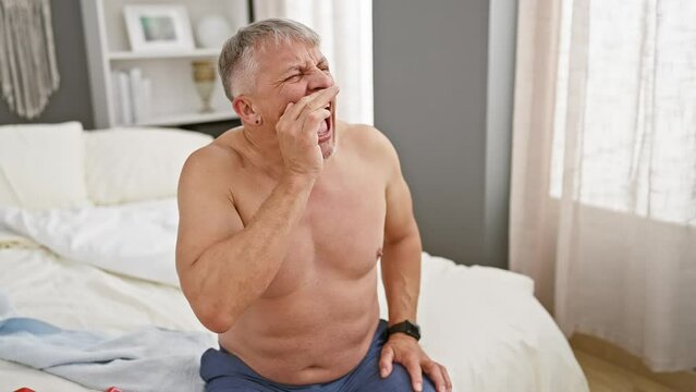Clueless grey-haired man in bed, shirtless with arms open in confused expression. elderly, bewildered, faces uncertainty with indifferent apology. at home, in room, shrugs off the unknown.