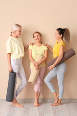 Mature women with yoga mats near beige wall