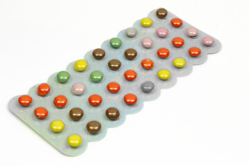 Colorful chocolate filled tablet pills candies in blister isolated on white background