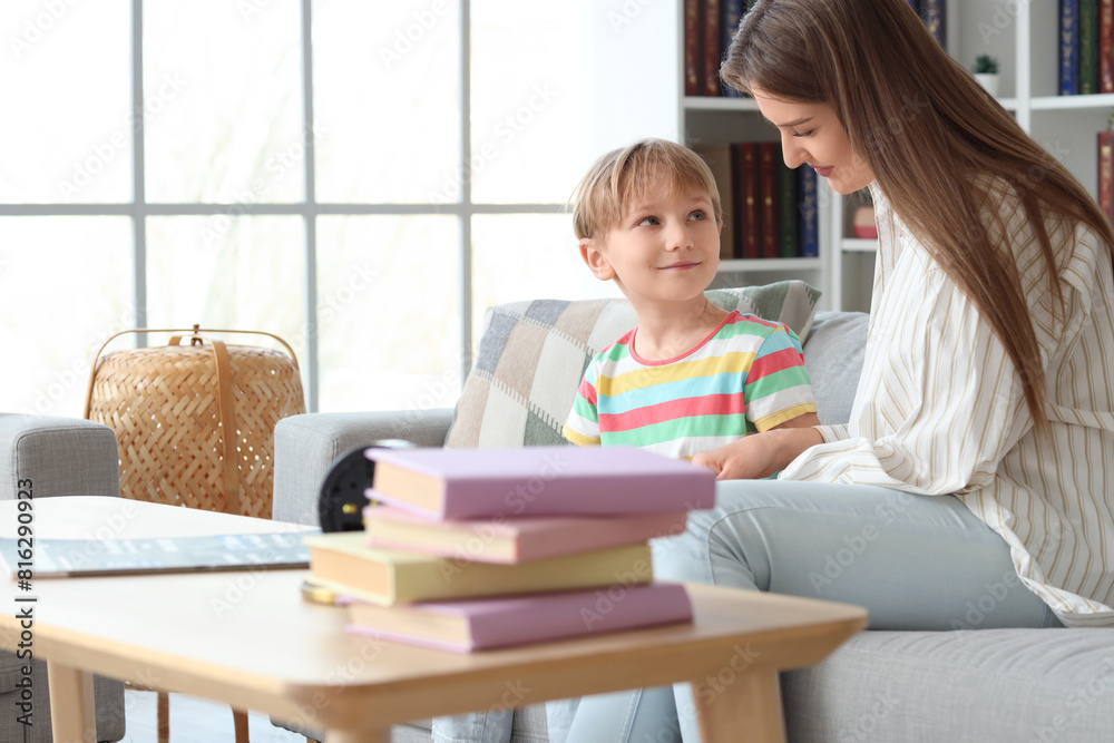 Poster Little boy with his mother reading book on sofa at home