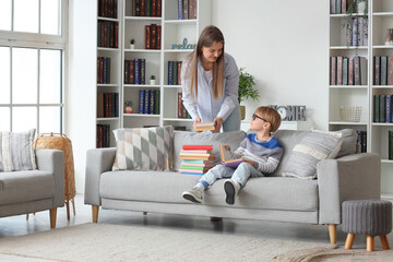 Cute little boy and his mother with different books at home