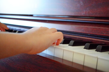 0歳小学4年生の子どもが電子ピアノを弾いている手元。