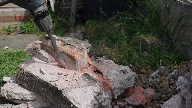 Breaking a concrete and brick block in half with hammer action power tool SDS chisel drill in slow motion