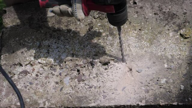 Close up of SDS hammer drill power tool drilling through concrete block in slow motion