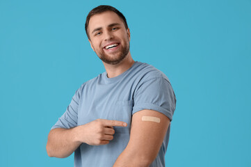 Young man with applied medical patch on blue background. Vaccination concept - Powered by Adobe