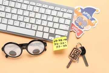 Carton key, sticky note, funny glasses and computer keyboard on beige background. April Fools Day...