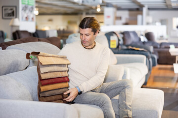 Man picking upholstery material in furniture store