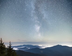 Fototapeta premium a night sky filled with stars and a mountain range in the distance.