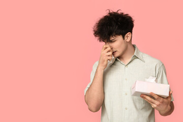 Young man with runny nose on pink background. Allergy concept