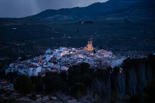 View from the hill of medieval historical urban village of Quesada in the province of Jaen, at dawn with the illuminated bell tower and while houses. Beauty in Spain nature. Travel and tourism concept