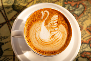 Close-up barista coffee with swan pattern in white cup on a table