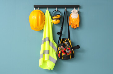 Safety vest, hardhat and tools hanging on blue wall