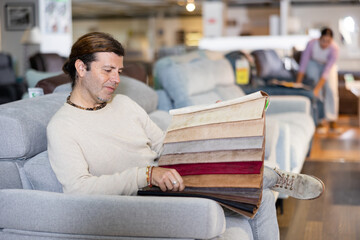 Portrait of man choosing upholstery fabric of furniture in the furniture salon