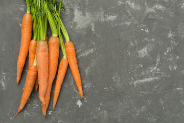 Bunch of fresh carrots on concrete background, top view