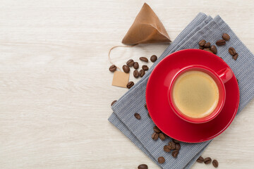 Cup of coffee made using pyramid on wooden background, top view