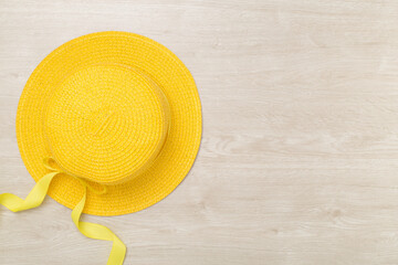 Yellow hat on wooden background, top view. Summer concept