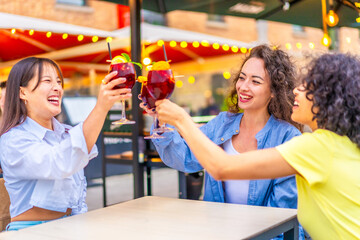 Women toasting with cocktails a sidewalk bar