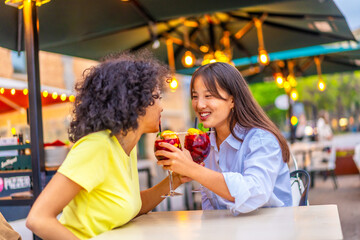 Romantic lesbian couple drinking cocktail together in an outdoor terrace