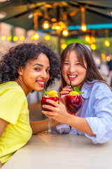 Lesbian multi-ethnic couple enjoying cocktails in an outdoor terrace