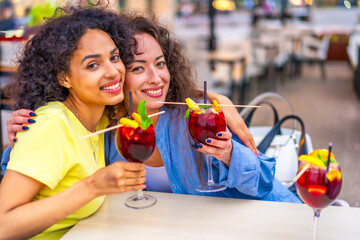 Friends embracing while drinking cocktails in a bar