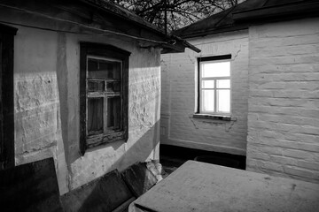 A rural house, night outside, the light from the window brightly illuminates the wall of the neighboring house.