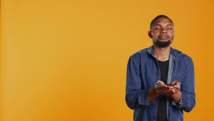Coffee enthusiast looks at aromatic roasted beans against orange background, promoting cold brew at a coffee shop or cafeteria. Enjoying eco friendly delicious black seeds. Camera B.