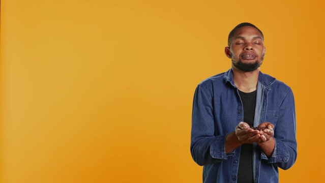 Coffee enthusiast looks at aromatic roasted beans against orange background, promoting cold brew at a coffee shop or cafeteria. Enjoying eco friendly delicious black seeds. Camera B.