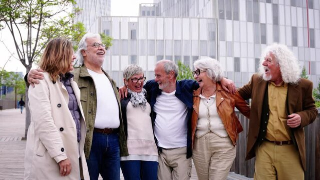 Group of smiling mature people walking carefree. Senior enjoy vacations on street of urban park city. Diverse happy elderly friends having fun celebrating leisure time hugging. Caucasian Gray hair