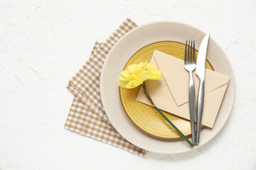 Stylish table setting with beautiful flower and envelope on white background