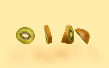 Fresh cut kiwi flying on color background